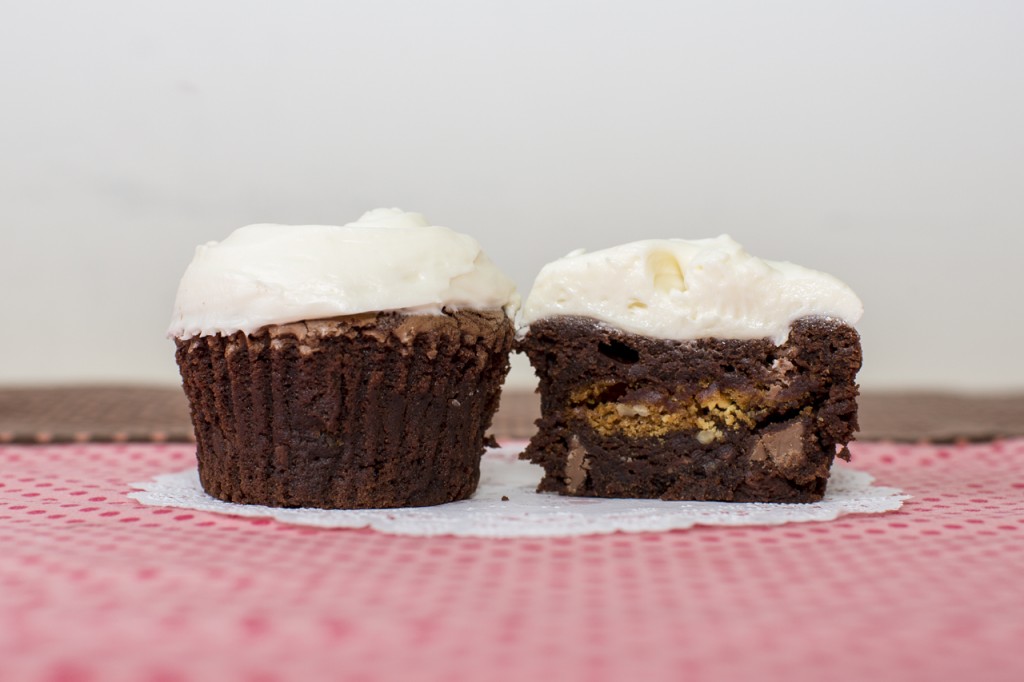 Brownie cupcake with white chocolate pecan cookie inside topped with white chocolate cream cheese frosting